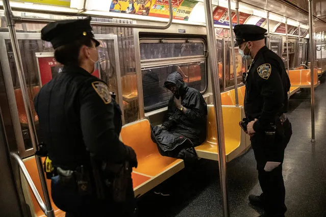 New York City Police (NYPD) officers wake up a passenger, during the coronavirus disease (COVID-19) outbreak in New York City, New York, U.S., May 6, 2020. (Photo by Jeenah Moon/Reuters)