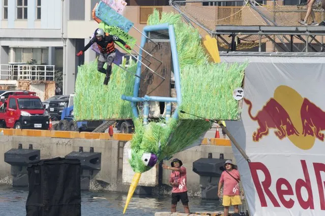 A team member jumps from a platform with a man made flying machine into the harbor in Taichung, a port city in central Taiwan on Sunday, September 18, 2022. (Photo by Szuying Lin/AP Photo)