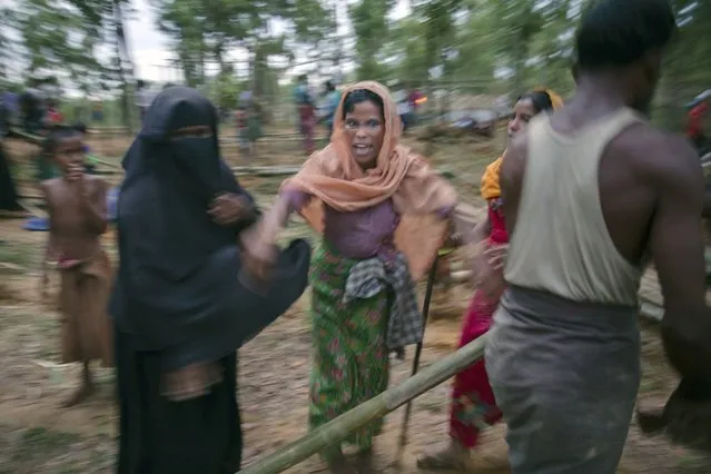 Rohingya Muslim women, who crossed over from Myanmar into Bangladesh, fight over a bamboo meant for constructing shelter for themselves at Kutupalong refugee camp, in Bangladesh, Wednesday, October 18, 2017. More than 580,000 refugees have arrived in Bangladesh since Aug. 25, when Myanmar security forces began a scorched-earth campaign against Rohingya villages. Myanmar's government has said it was responding to attacks by Muslim insurgents, but the United Nations and others have said the response was disproportionate. (Photo by Dar Yasin/AP Photo)