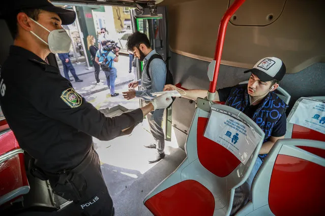 An Azeri law enforcement officer distributes free reusable face masks on a bus during the pandemic of the novel coronavirus disease (COVID-19) in Baku, Azerbaijan on May 27, 2020. The coronavirus outbreak has infected more than 5 million people across the world. Azerbaijan has reported 4,403 cases of COVID-19 and 52 deaths.(Photo by Aziz Karimov/Getty Images)