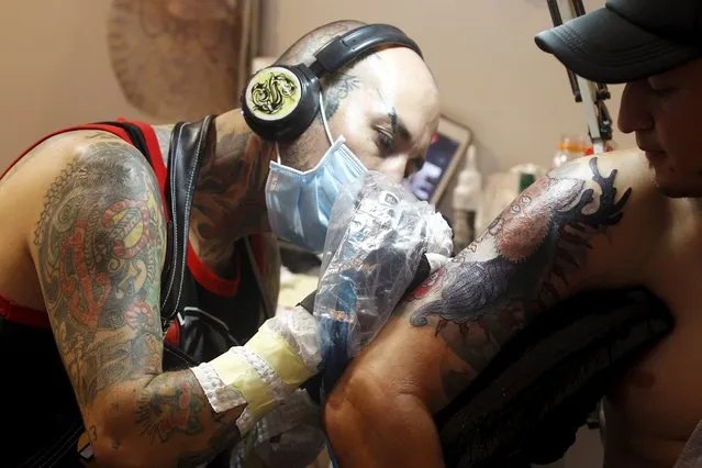 Tattoo artists work on a piece during the Cali Tattoo Festival in Cali, Colombia, September 13, 2015. (Photo by Jaime Saldarriaga/Reuters)