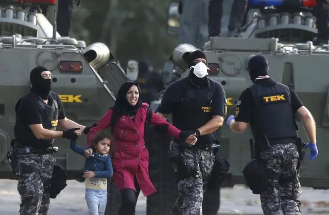 Hungarian riot policemen escort a migrant woman and a child in Roszke, Hungary September 16, 2015. (Photo by Dado Ruvic/Reuters)