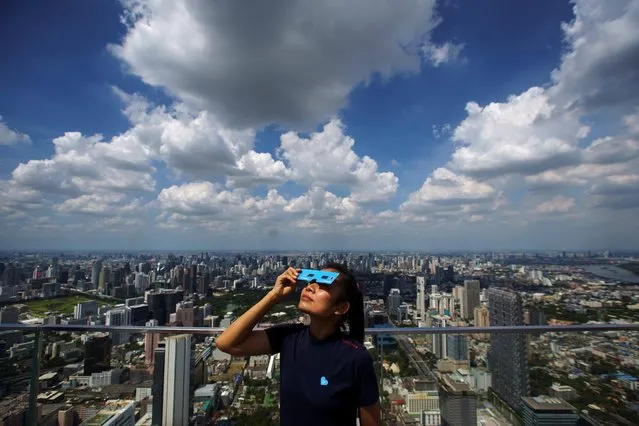 A woman observes a partial solar eclipse on the Mahanakhon Skywalk Glass Tray at the King Power Mahanakhon building in Bangkok, Thailand, June 21, 2020. (Photo by Athit Perawongmetha/Reuters)