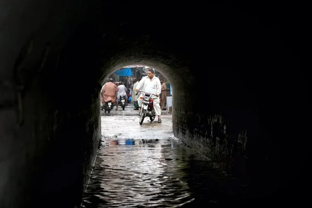 A man makes his way through an inundated tunnel following heavy rains, in Lahore, Pakistan, 25 August 2016. (Photo by Rahat Dar/EPA)