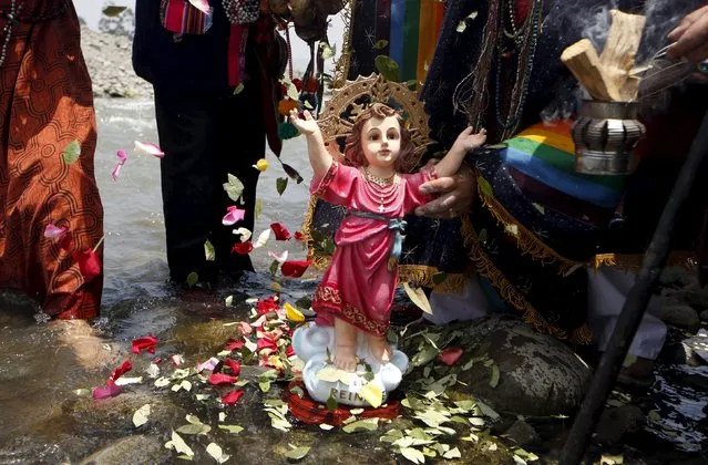 Peruvian shamans holding a figure of a Nino Jesus (Child Jesus) perform a ritual at the Rimac river to fight the negative effects of the Nino weather phenomena over Nature, in Lima, Peru October 1, 2015. (Photo by Mariana Bazo/Reuters)