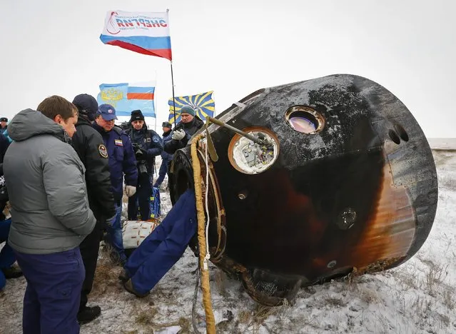 Ground personnel work next to the Soyuz TMA-13M capsule of the International Space Station (ISS) crew of Alexander Gerst of Germany, Maxim Suraev of Russia and Reid Wiseman of the U.S. after its landing near the town of Arkalyk in northern Kazakhstan November 10, 2014. (Photo by Shamil Zhumatov/Reuters)