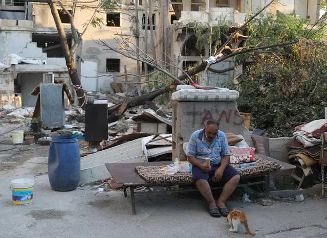 A man eats in front of a house destroyed by the blast in Beirut, Lebanon, August 16, 2020. (Photo by Goran Tomasevic/Reuters)