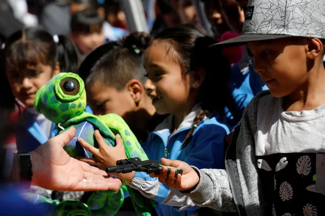 A child exchanges a toy gun during a voluntary disarming program run by the government with the support of the Army and the Catholic Church, which aims to swap toy weapons for fluffy toys outside the Metropolitan Cathedral in Mexico City, Mexico January 22, 2018. (Photo by Carlos Jasso/Reuters)