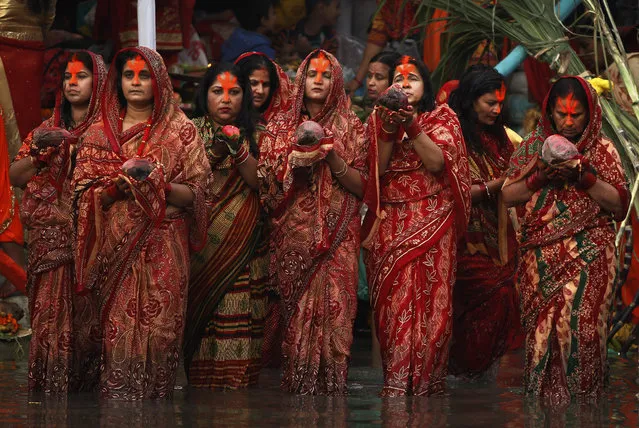 Nepalese women hold coconuts and offer prayers to the setting sun on the banks of the Bagmati River during the Chhath Puja festival in Kathmandu, Nepal, Thursday, October 26, 2017. During Chhath, an ancient Hindu festival, rituals are performed to thank the Sun God for sustaining life on earth. (Photo by Niranjan Shrestha/AP Photo)