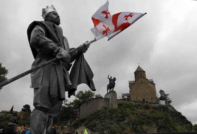 An actor dressed as Vakhtang I "Gorgasali," a king of Iberia, holds a Georgian national flag in front of the Metekhi Church and a monument to Vakhtang I "Gorgasali," during the annual Tbilisoba City Day celebration in Tbilisi, Georgia, Saturday, October 17, 2015. Tbilisoba is an annual October festival, celebrating the diversity and history of Tbilisi, the capital of Georgia. (Photo by Shakh Aivazov/AP Photo)