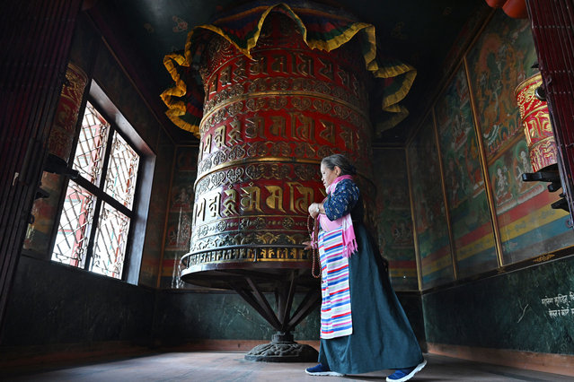 A Buddhist devotee spins a large prayer wheel at the Boudhanath Stupa on the outskirts of Kathmandu on July 2, 2025. Exiled Tibetan spiritual leader the Dalai Lama said on July 2, at the start of the 15th Tibetan Religious Conference, that the 600-year-old institution will continue after his death, a decision that will have profound impact on his Buddhist followers. (Photo by Prakash Mathema/AFP Photo)