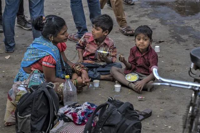 Children of daily wage laborers eat breakfast as their parents wait to get hired in Mumbai, India, Wednesday, February 1, 2023. (Photo by Rafiq Maqbool/AP Photo)