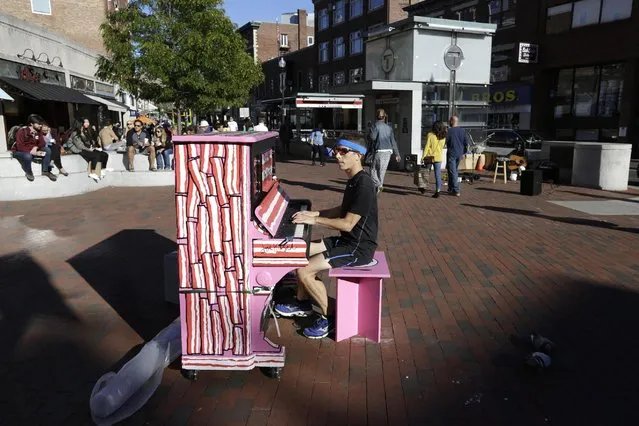 In this Sunday, September 25, 2016 photo Scott Frazer, of Medford, Mass., plays a piano on the sidewalk in the Harvard Square neighborhood of Cambridge, Mass. A number of working pianos painted by local artists have been placed around Boston and Cambridge, each with a simple message to passersby: “Play Me, I'm Yours”. (Photo by Steven Senne/AP Photo)
