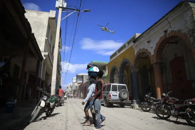 A USN helicopter flies overhead during a protest against the arrival of the USNS Comfort hospital ship in Jeremie, Haiti, Tuesday,December 13, 2022. (Photo by Joseph Odelyn/AP Photo)