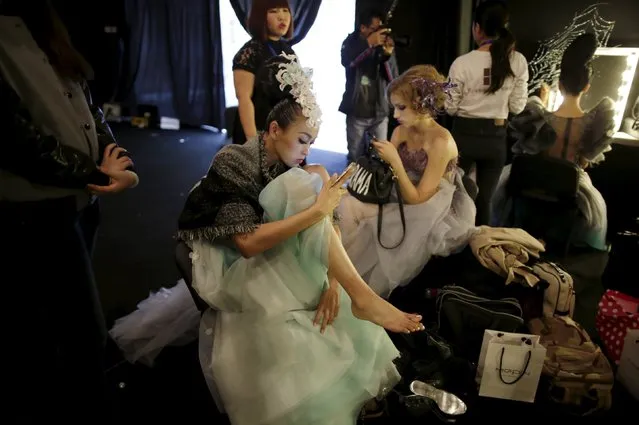 Models play their mobile phones backstage before a colorful cosmetic fashion trend collection by Chinese designer Mao Geping at China Fashion Week S/S 2016, in Beijing, China, October 26, 2015. (Photo by Jason Lee/Reuters)