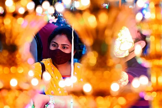 A woman shops for decorative items at a roadside market ahead of the Hindu festival Diwali, the festival of lights, in Kolkata on November 7, 2020. (Photo by Dibyangshu Sarkar/AFP Photo)