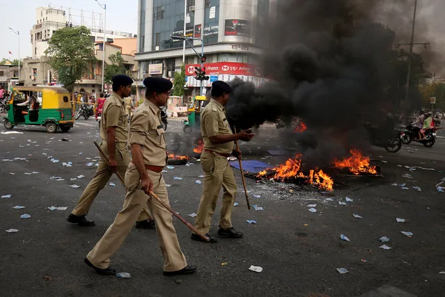 Police officers patrol a street after people belonging to the Dalit community burned tyres and hoardings during a nationwide strike called by Dalit organisations, in Ahmedabad, April 2, 2018. (Photo by Amit Dave/Reuters)