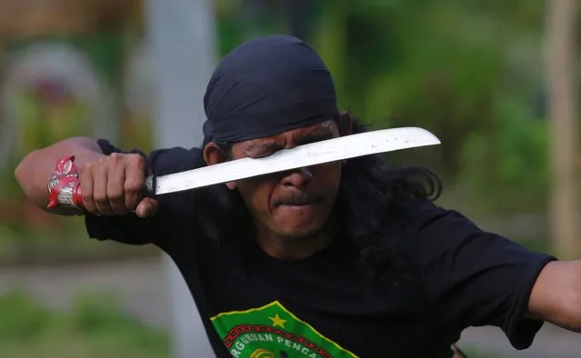 A man slashes his eyes with a machete as he perform Debus martial art at a field in Tangerang, Indonesia, 17 December 2020. Debus martial art is the oldest martial art in Banten province. This martial art requires superhuman inner strength because the thing that is most highlighted is a show that displays the immunity of the human body against the torture of various sharp objects. (Photo by Adi Weda/EPA/EFE)