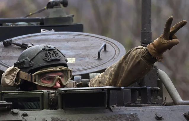 A Ukrainian serviceman flashes a victory sign as he drives towards the frontline during heavy fighting at the frontline of Bakhmut and Chasiv Yar, in Chasiv Yar, Ukraine, April 12, 2023. (Photo by Kai Pfaffenbach/Reuters)