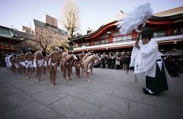A shinto priest prays for the shrine parishioners before pouring cold water onto themselves during an annual cold-endurance festival at the Kanda Myojin Shinto shrine in Tokyo, Saturday, January 10, 2015. (Photo by Eugene Hoshiko/AP Photo)