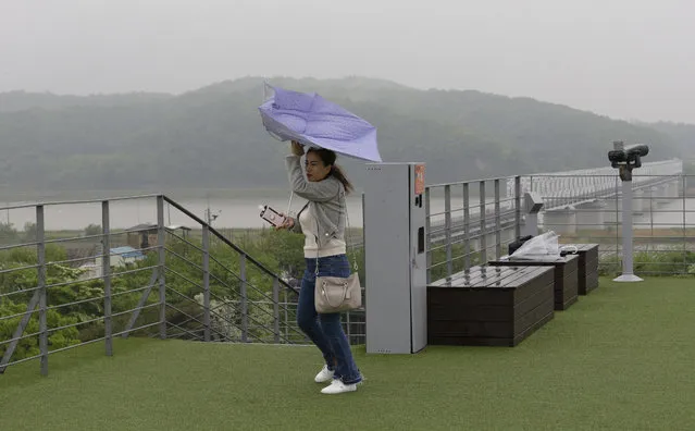 A visitor tries to hold her umbrella in rain and strong wind at the Imjingak Pavilion in Paju near the border village of Panmunjom, South Korea, Wednesday, May 16, 2018. (Photo by Ahn Young-joon/AP Photo)