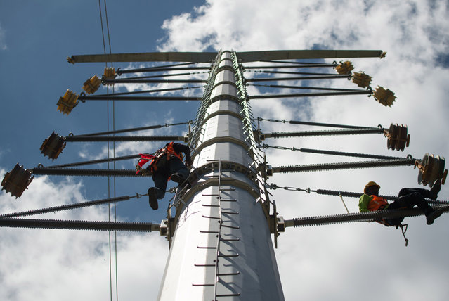 Workers climb as they prepare to install new high-voltage electric power transmission line on an electric pylon in Kuala Lumpur on January 15, 2015. Currently 16% of Malaysian electricity generation is hydroelectric, the remaining 84% being thermal. The oil and gas industry in Malaysia is currently dominated by state owned Petronas. (Photo by Mohd Rasfan/AFP Photo)