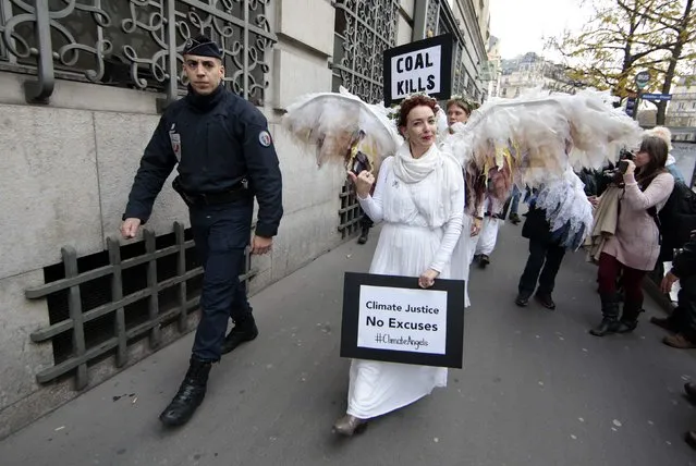 A French police officer escorts Australian environmental activists called Climate Guardian Angels during a demonstration as part of the World Climate Change Conference 2015 (COP21) in Paris, France, December 3, 2015. (Photo by Eric Gaillard/Reuters)