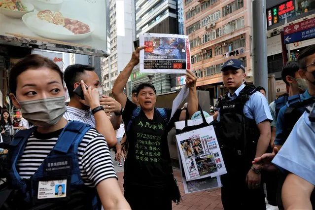 Police detain a woman who holds placards to promote knee maintenance in downtown Hong Kong on the 34th anniversary of the 1989 Beijing Tiananmen Square crackdown, near the location where the candlelight vigil is usually held, in Hong Kong, China on June 4, 2023. (Photo by Tyrone Siu/Reuters)