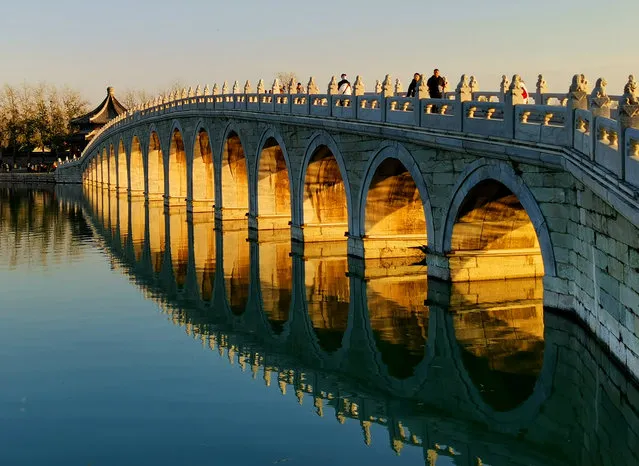 The setting sun shines through the Seventeen-Arch Bridge at the Summer Palace on November 24, 2020 in Beijing, China. (Photo by Gong Wenbao/VCG via Getty Images)