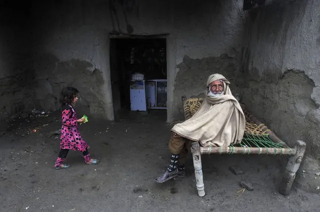 Abdul Karim, 75, covers himself from the cold while sitting on a rope bed near a shop on the outskirts of Peshawar January 22, 2015. (Photo by Fayaz Aziz/Reuters)