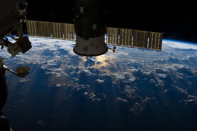 In this photo released on July 9, 2013, one of the Expedition 36 crew members aboard the International Space Station records a large mass of storm clouds over the Atlantic Ocean near Brazil and the Equator on July 4, 2013. A Russian spacecraft, docked to the orbiting outpost, partially covers a small patch of sunglint on the ocean waters in a break in the clouds. (Photo by NASA)