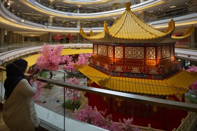 A women wearing a face mask take photos of the Summer Palace structures ahead of the Chinese New Year decorations at a shopping mall in Petaling Jaya, Malaysia, Wednesday, January 20, 2021. Malaysian Prime Minister Muhyiddin Yassin has unveiled a new 15 billion ringgit ($3.7 billion) stimulus to bolster consumption, with the economy expected to reel from a second coronavirus lockdown and an emergency declaration. (Photo by Vincent Thian/AP Photo)