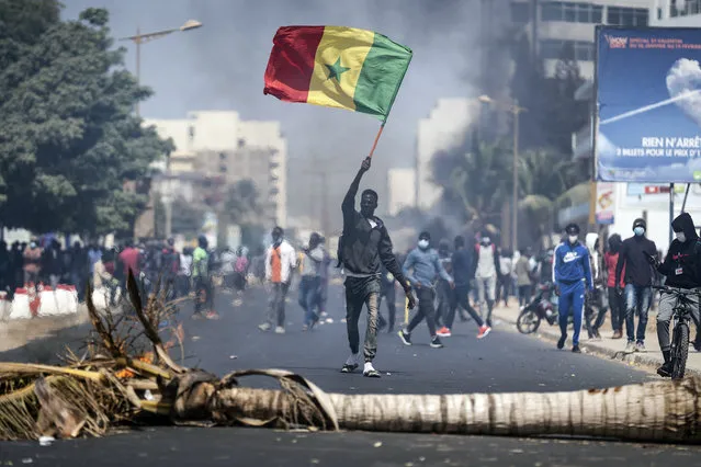 A demonstrator waves a Senegalese national flag during protests in support of main opposition leader and former presidential candidate Ousmane Sonko in Dakar, Senegal, Wednesday, March 3, 2021. (Photo by Leo Correa/AP Photo)