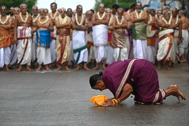 A devotee offers prayers as priests watch while taking part in the chariot festival of Sri Parthasarthy Swamy temple in Chennai on July 3, 2023. (Photo by R. Satish Babu/AFP Photo)
