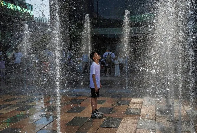 A boy stands in a water fountain as he cools off at shopping mall during a heatwave on June 23, 2023 in Beijing, China. Authorities issued a red alert for high temperatures, the highest in the country's four tier system, as China's capital and other parts of northern China saw scorching temperatures hovering around 40 degrees Celsius. (Photo by Kevin Frayer/Getty Images)