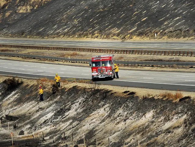 Firefighters look over a burned area along Highway 101 in Ventura, Calif., Saturday, December 26, 2015. A wind-whipped wildfire closed a major coastal highway in Southern California and forced dozens of homes to be evacuated, authorities said Saturday. No injuries or damages were reported. (Photo by Chuck Kirman/The Ventura County Star via AP Photo)