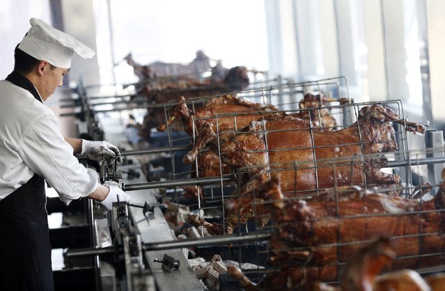 A cook controls a machine to grill lamb meats at a Mongolian style restaurant Nine-Nine Yurts in Beijing February 10, 2015. China is the world's largest producer of lamb and mutton, with a flock estimated at nearly 140 million in 2011, but output has been declining as farmable land shrinks due to urbanisation. (Photo by Kim Kyung-Hoon/Reuters)