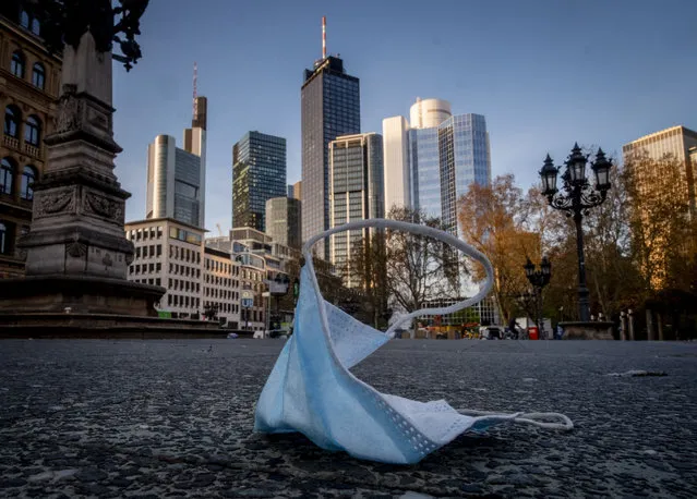 A face mask is left back on the opera square in Frankfurt, Germany, Saturday, April 24, 2021. From the weekend on a curfew becomes effective to avoid the outspread of the coronavirus. (Photo by Michael Probst/AP Photo)