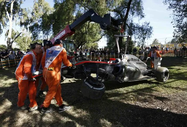 Course officials remove the car of McLaren Formula One driver Kevin Magnussen of Denmark after he crashed during the second practice session of the Australian F1 Grand Prix at the Albert Park circuit in Melbourne March 13, 2015.   REUTERS/Jason Reed
