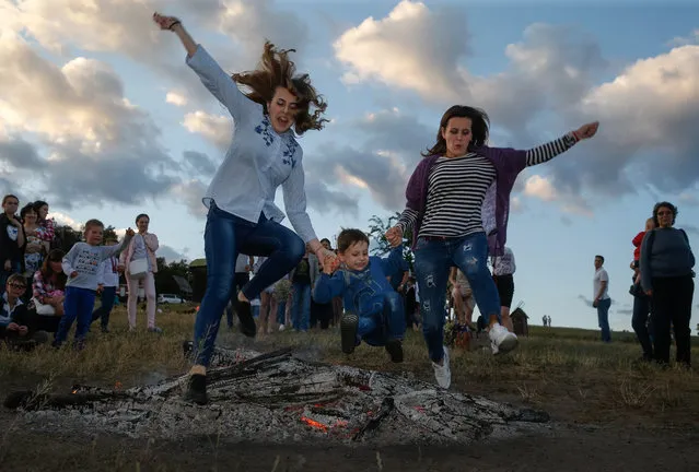 Ukrainians jump over a fire in Kiev, Ukraine, 06 July 2017, as they celebrate the traditional pagan holiday of Ivana Kupala. Ivana Kupala is celebrated, during the summer solstice, on the shortest night of the year, marking the beginning of summer and is celebrated in Ukraine, Belarus, Poland and Russia on the night of 06 July. People sing and dance around bonfires, play games and perform traditional rituals. Young people jump over bonfires in order to test their bravery. Couples holding hands jump over the flames to test their love. If the couple does not succeed it is predicted to split up. Traditionally, children and young unmarried women wear wreaths of wild flowers on their heads to symbolize purity. (Photo by Sergey Dolzhenko/EPA)