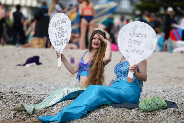 Demonstrators hold signs in a protest in Gyllyngvase beach, Falmouth, during the G7 summit in Cornwall, Britain, June 12, 2021. (Photo by Tom Nicholson/Reuters)