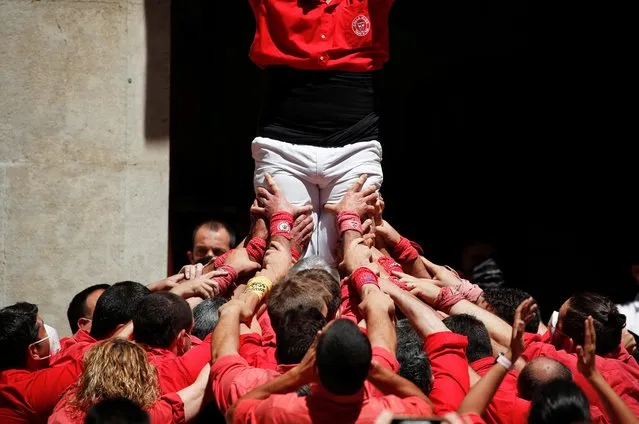 People form the foundation of a human tower during the first performance of Colla Joves Xiquets de Valls and Colla Vella Dels Xiquets de Valls after the coronavirus pandemic halt, at Blat square in Valls, Spain on June 24, 2021. (Photo by Albert Gea/Reuters)