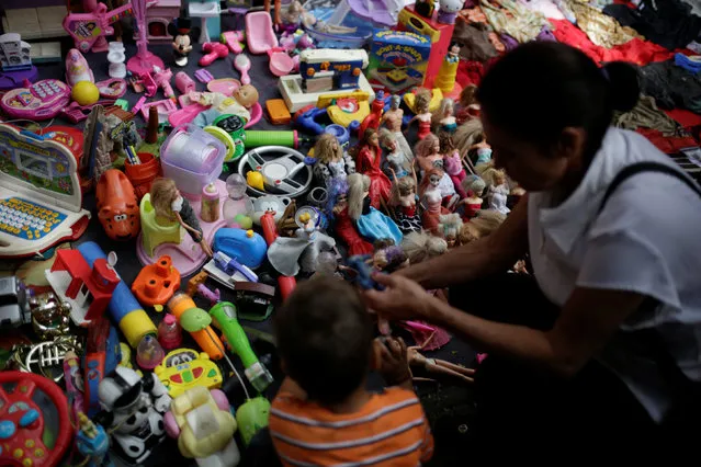 People look at second-hand toys at a street market in the slum of Catia in Caracas, Venezuela December 21, 2016. (Photo by Marco Bello/Reuters)