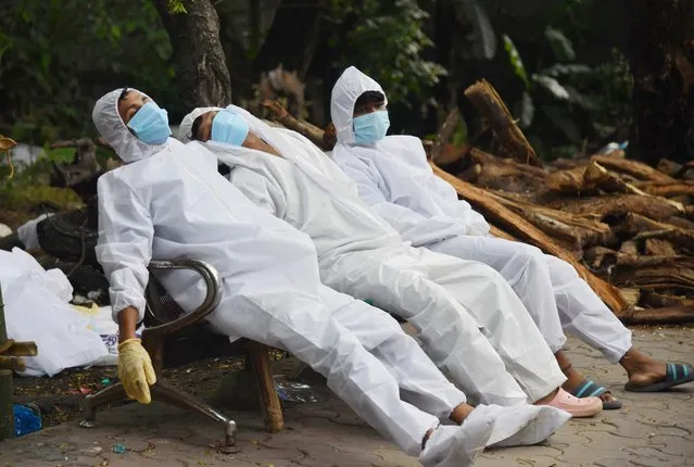 Ambulance staff rest on a bench after their Covid-19 coronavirus duty at a crematorium ground in Guwahati on June 25, 2021. (Photo by Biju Boro/AFP Photo)
