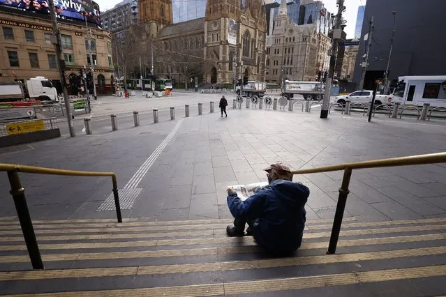 A man reads a newspaper on the steps of Flinders Street Station in Melbourne, Australia, Wednesday, August 11, 2021. Australia's second-largest city has extended its lockdown in a bid to eliminate COVID-19 while authorities in Sydney flagged restrictions easing for vaccinated residents despite the delta variant continuing to spread. (Photo by Daniel Pockett/AAP Image)