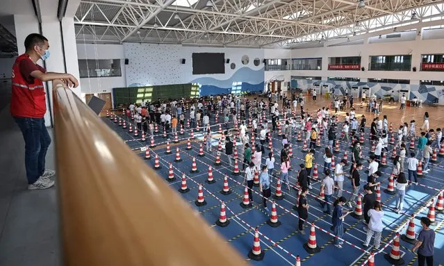 This photo taken on August 5, 2021 shows staff queueing to test for the Covid-19 coronavirus at the gym of a company in Wuhan in China's central Hubei province. (Photo by AFP Photo/China Stringer Network)