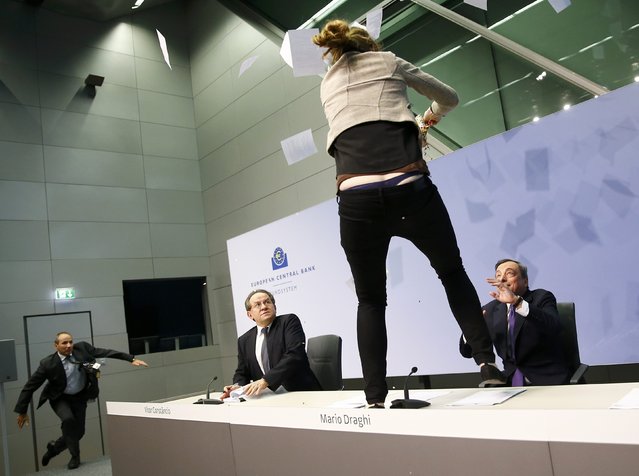 A protester jumps on the table in front of the European Central Bank President Mario Draghi during a news conference in Frankfurt, April 15, 2015. (Photo by Kai Pfaffenbach/Reuters)