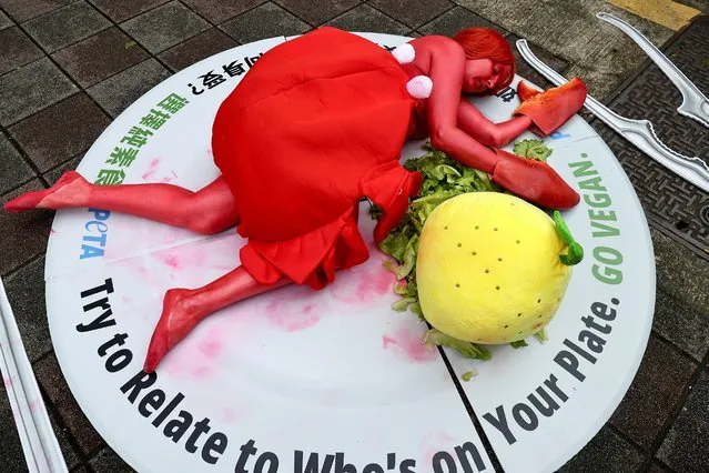 An animal rights activist bodypainted as a crab lies down in front of the fish market to encourage people to think about the food they eat, in Taipei, Taiwan on November 25, 2022. (Photo by Ann Wang/Reuters)