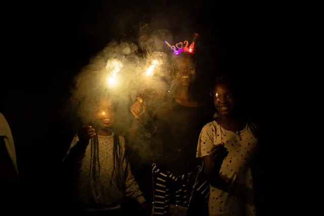 People celebrate with sparkles during the new year celebrations in Ijebu Imushin on January 1, 2024. (Photo by Samuel Alabi/AFP Photo)