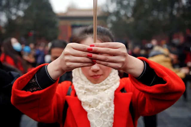 A woman holds incense sticks while praying at Yonghegong Lama Temple on the first day of the Lunar New Year of the Rooster in Beijing, China January 28, 2017. (Photo by Damir Sagolj/Reuters)